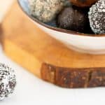 A coconut covered chocolate ball sitting on a white bench top.