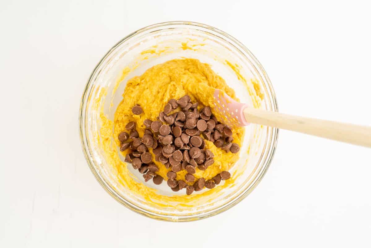 Pumpkin muffin batter in a glass bowl with chocolate chips.