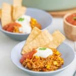 A bowl of mince and rice, garnished with sour cream, coriander and tortilla chips.