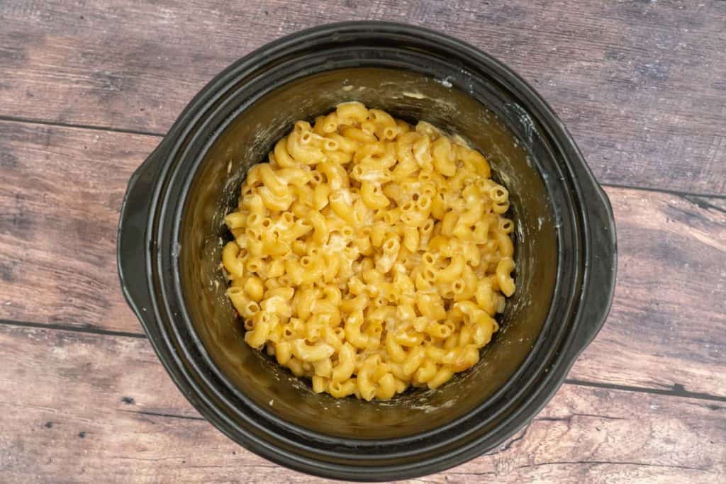 Cooked mac and cheese in a large black crockpot dish. 