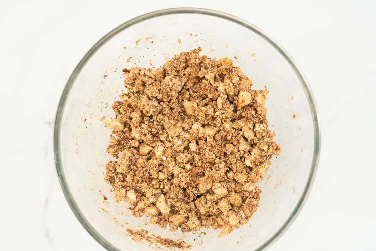 Crumbled tofu coated in a spice mix in a large glass mixing bowl