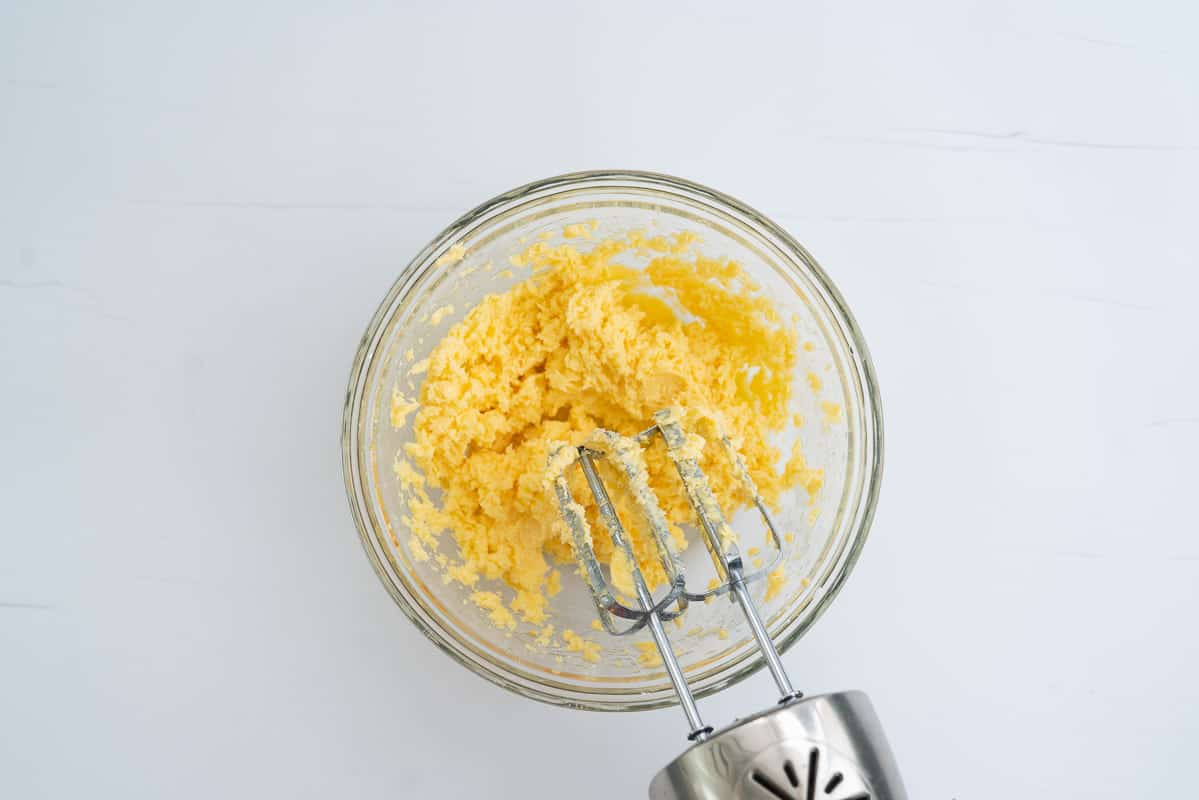 A glass mixing bowl of creamed butter, sugar and egg.