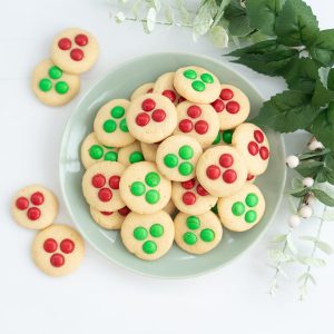 A gren plate filled with red and green candy decorated Christmas cookies