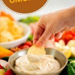 A hand holding a chip loaded with dip above a bowl of kiwi onion dip, with text overlay