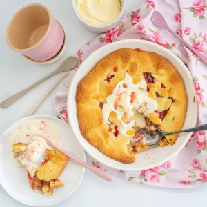 A rhubarb pie in a white pie dish, topped with a scoop of melted ice cream.