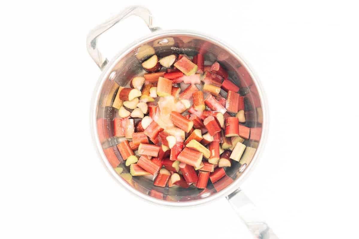 Small pieces of rhubarb in a saucepan with water and sugar