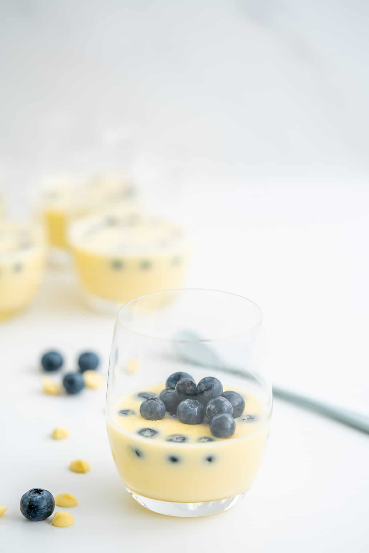 A glass filled with white chocolate mousse garnished with fresh blueberries