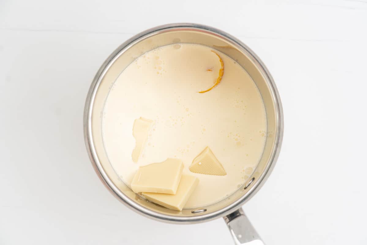 Cream, pieces of white chocolate and lemon zest in a saucepan.