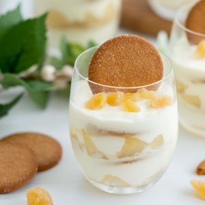 A layered dessert of yogurt, pears and ginger nut biscuits in a glass.