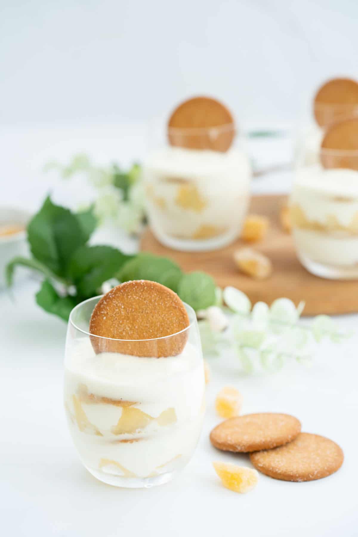 A layered dessert of yogurt, pears and ginger nut biscuits in a glass.
