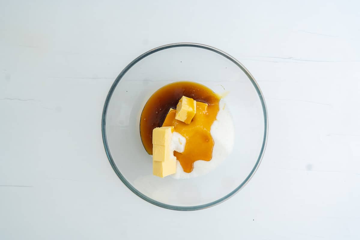 Cubes of butter, caster sugar and golden syrup in a large glass mixing bowl. 