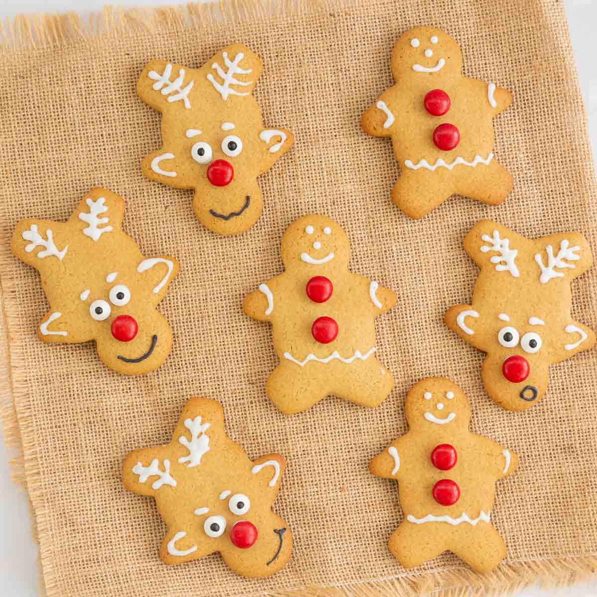 Gingerbread cookies and reindeer cookies sitting on a brown hessian cloth. 