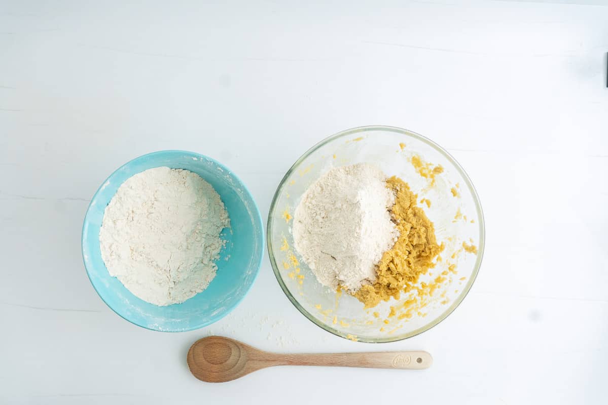 Blue mixing bowl of dry ingredients, next to a bowl of wet ingredients in a glass mixing bowl.