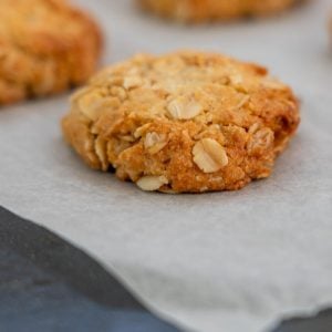 Golden Anzac biscuits on a baking paper lined cookie sheet.