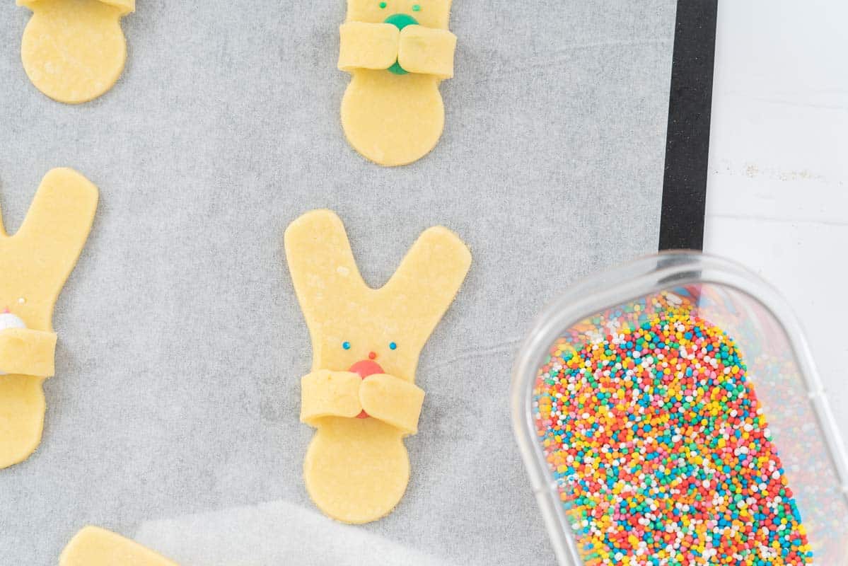 Cookies decorated to look like easter bunnies holding easter eggs. 