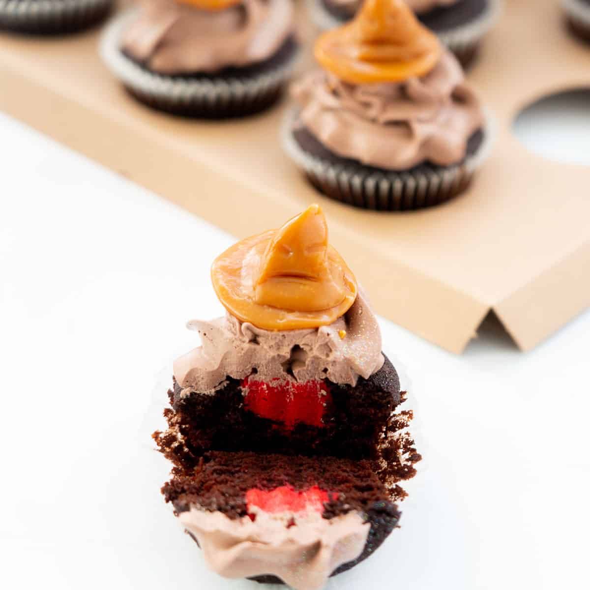 A sorting hat cupcake cut in half to reveal its hidden red butter cream filling.