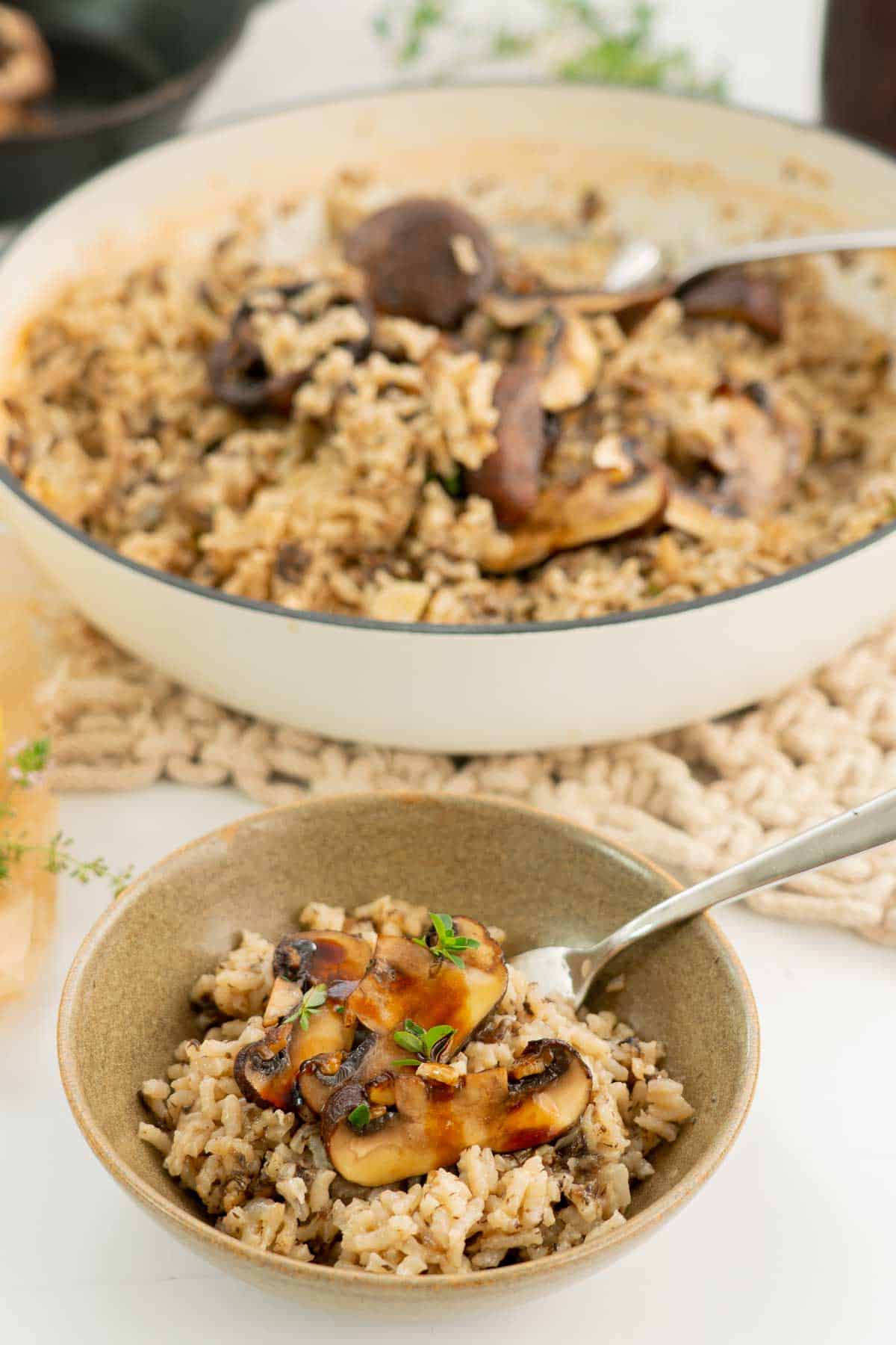 a serving of mushroom risotto on a table with a large dish of risotto.