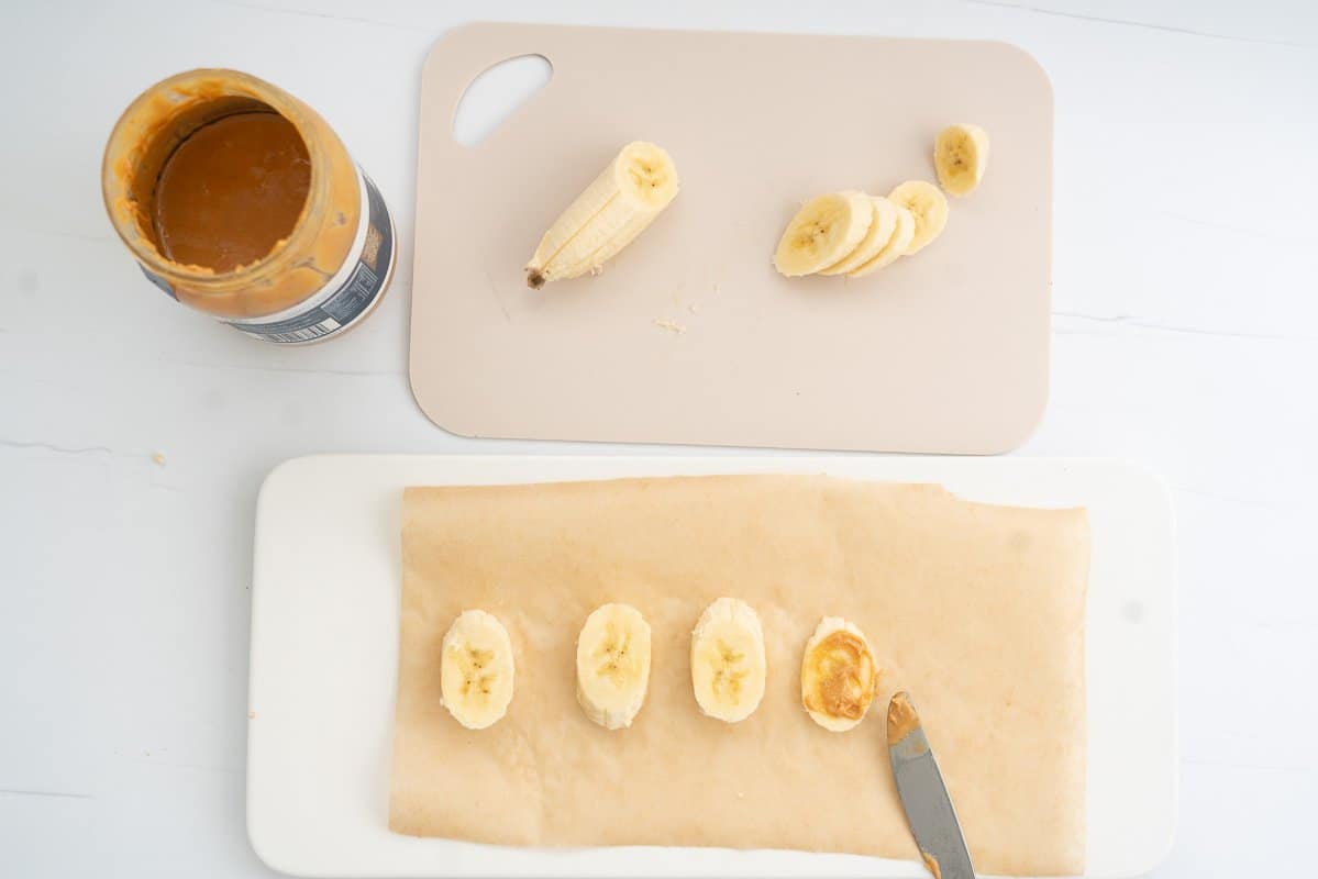 Banana slices being spread with peanut butter.