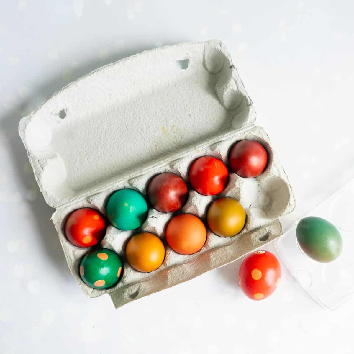An egg carton filled with 12 coloured eggs.
