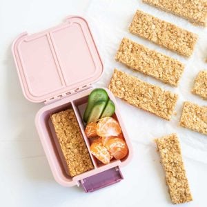 Oatmeal bars packed in to a pink lunch box with cucumber and mandarin segments