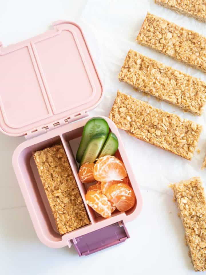 Oatmeal bars packed in to a pink lunch box with cucumber and mandarin segments