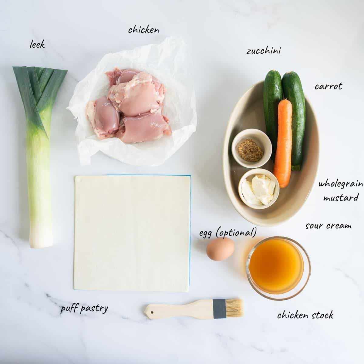 The ingredients to make chicken leek pie laid out on a bench top with text overlay.