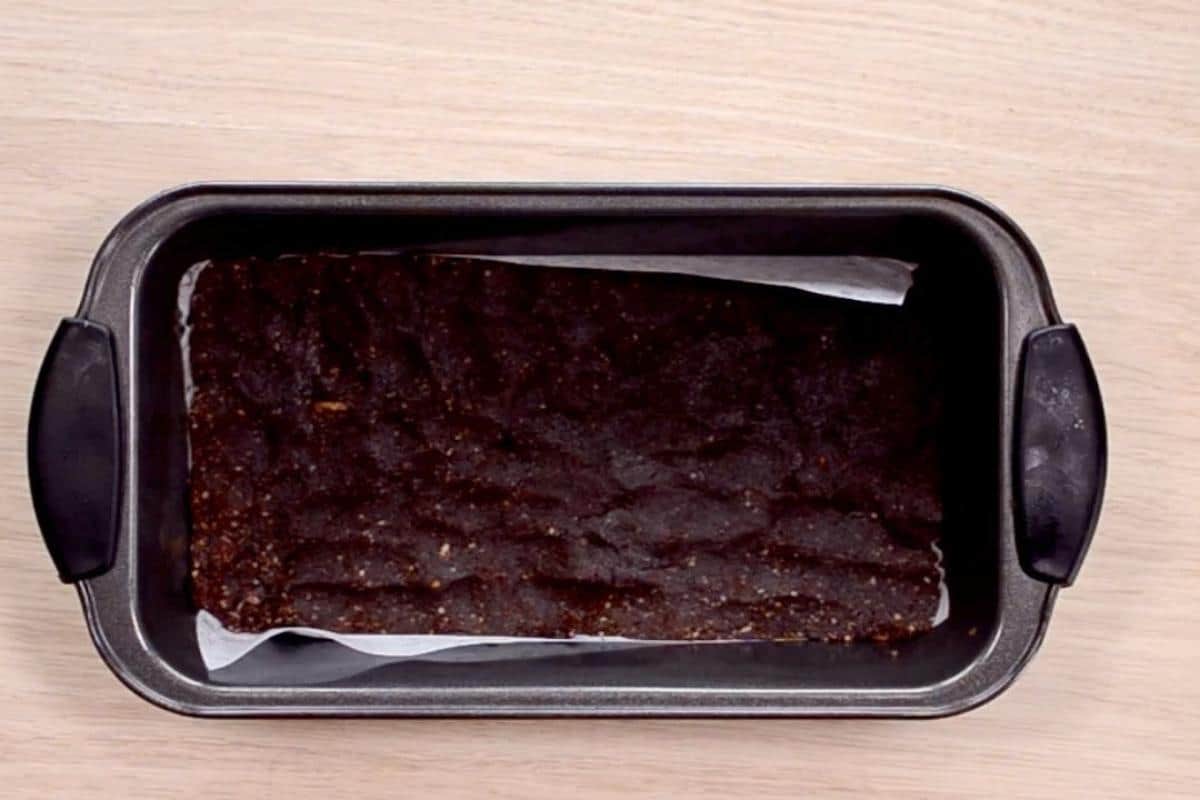 Chocolate slice pressed into the bottom of a lined loaf tin. 