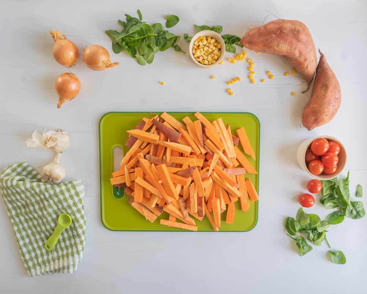 Orange kumara battens pilled on a green chopping board.