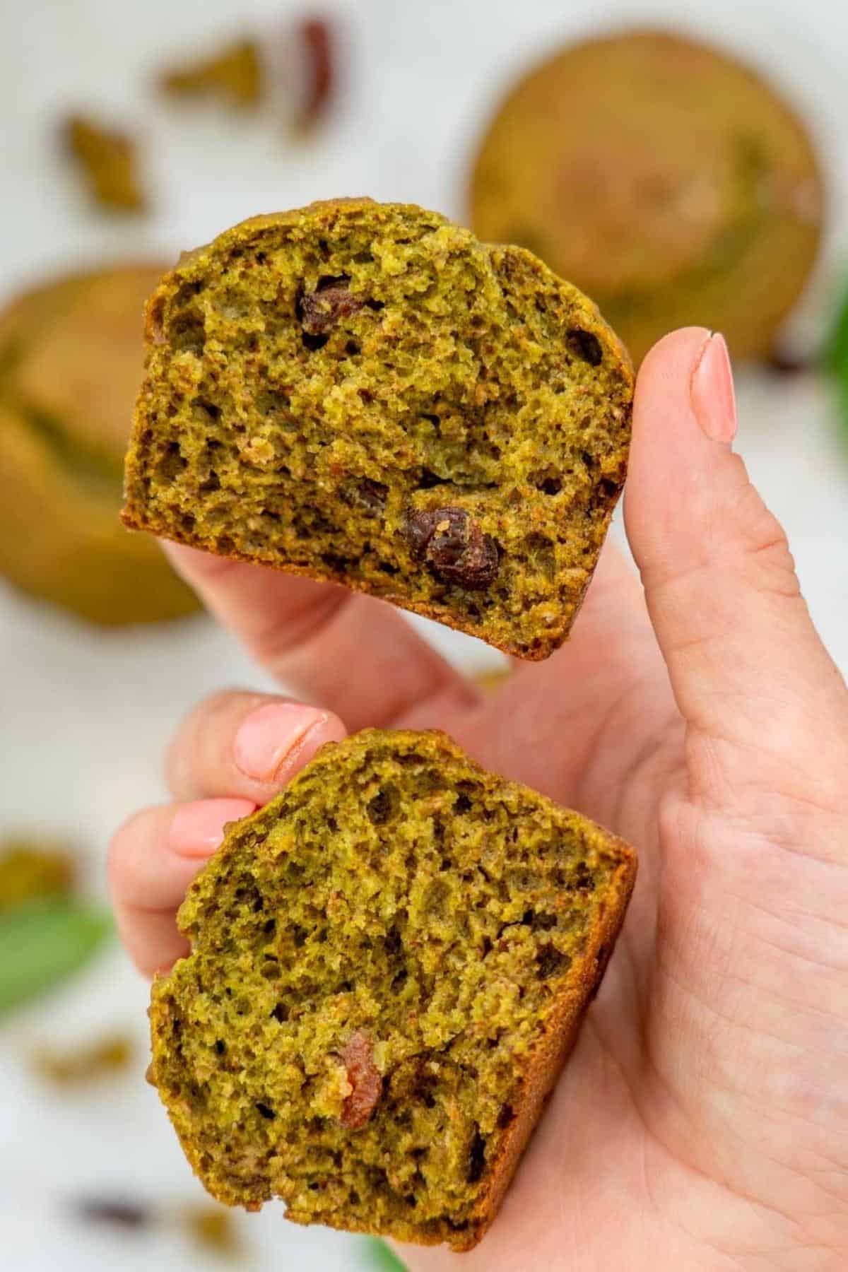 A muffin broken in half to reveal it's inside texture,  raisins visible.