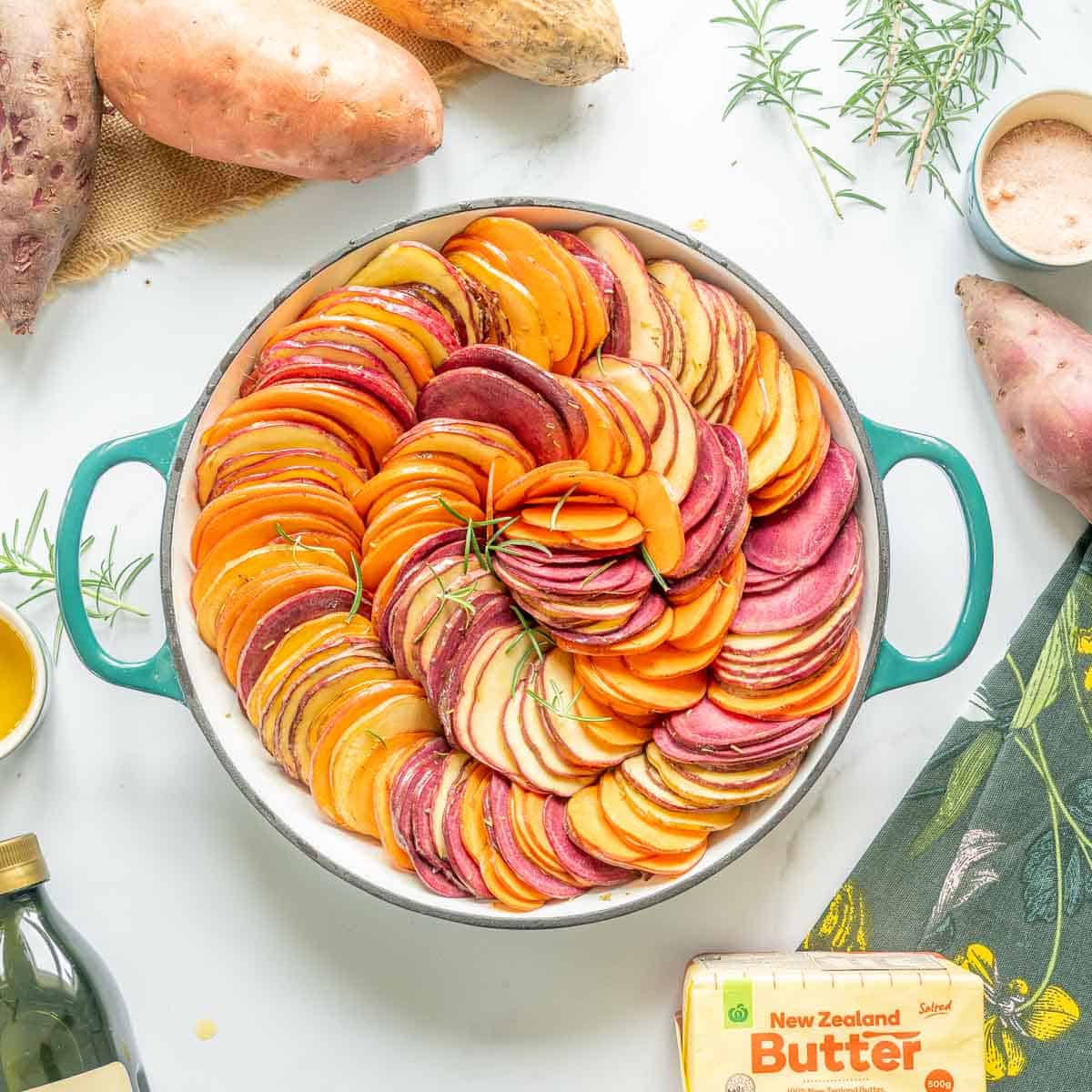 Thinly sliced kumara arranged in a spiral configuration in a round baking dish. 