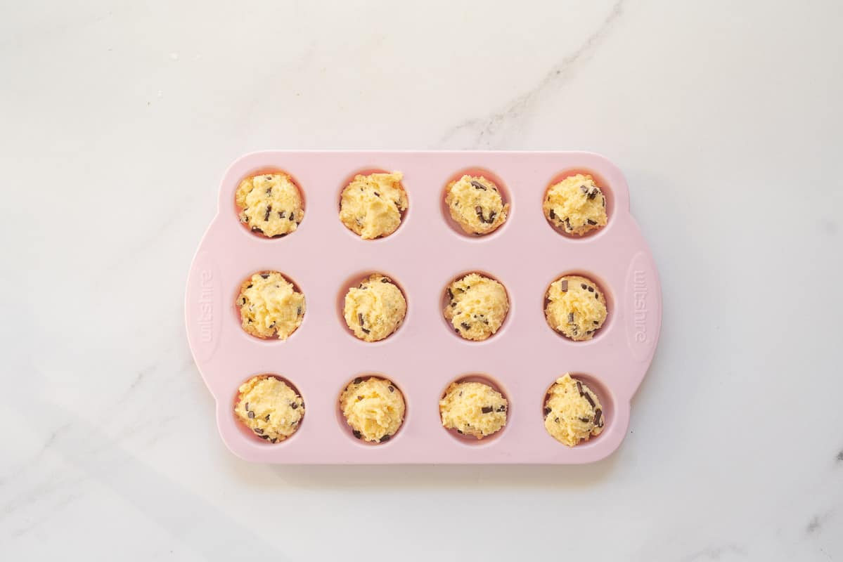 Muffin batter portion into a pink silicone mini muffin tray. 