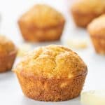 A golden muffin sitting on a white marble bench top next to a small piece of canned pineapple.