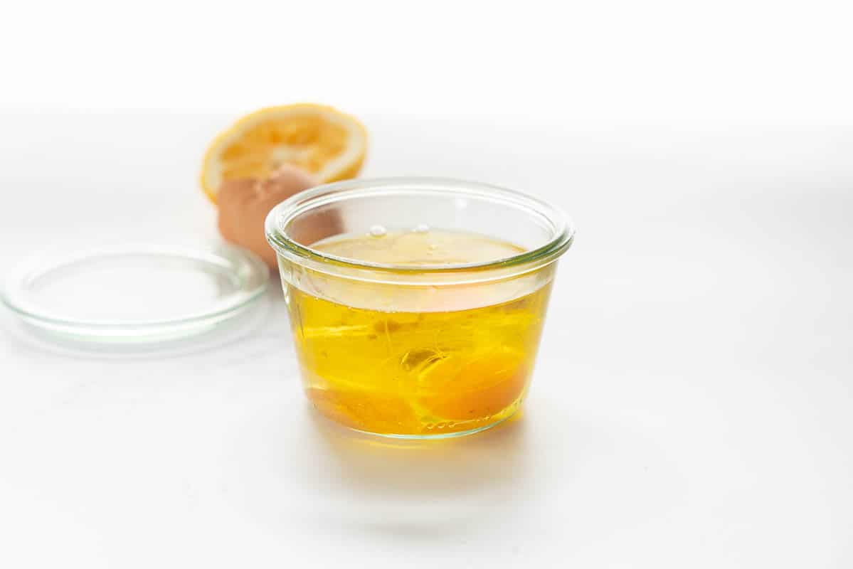 A wide mouthed jar containing a raw egg and oil.