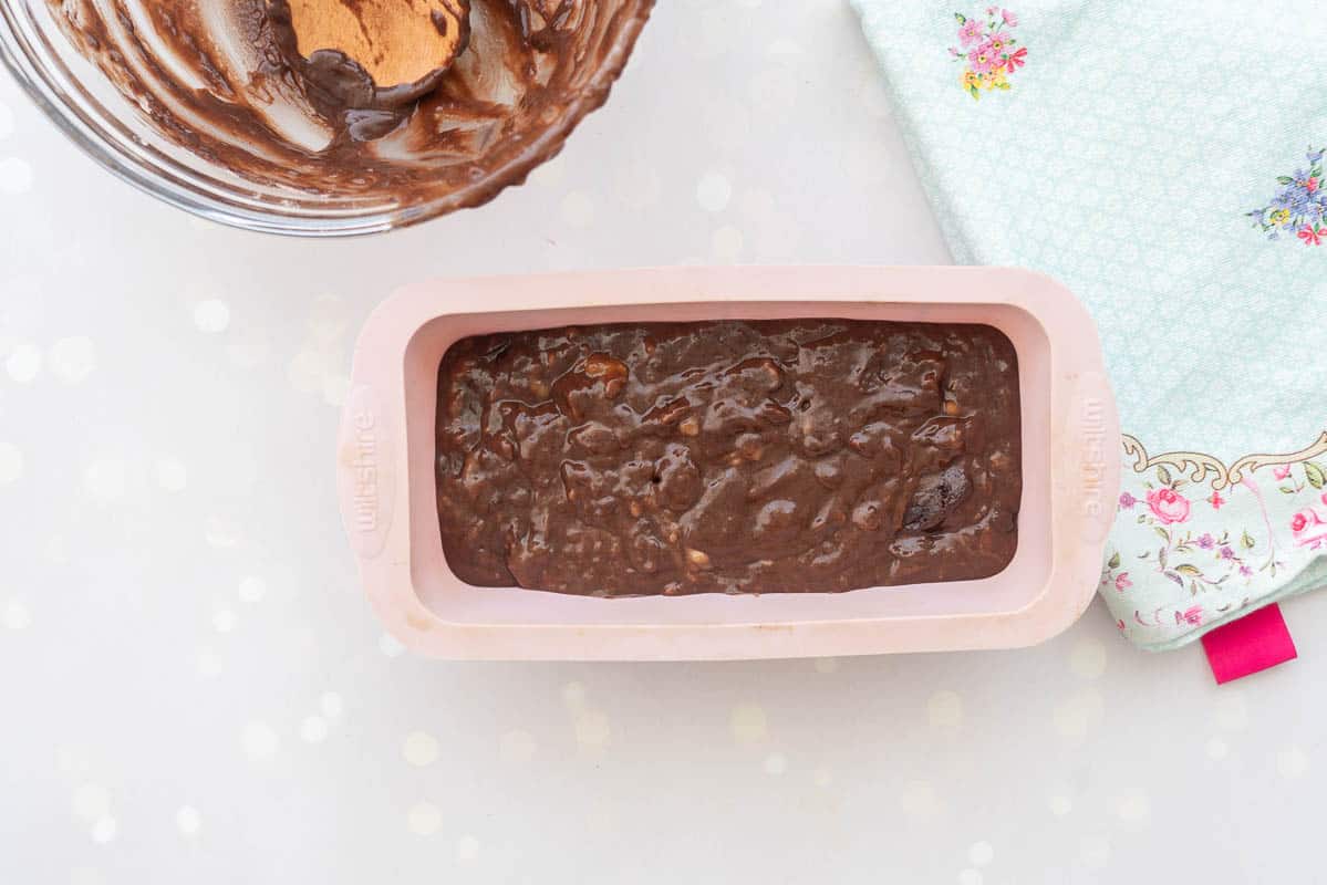 Banana bread batter in a pink silicone loaf tin ready to be baked in the oven. 