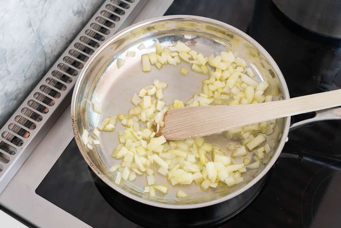 Onions cooking in a stainless steel fry pan.