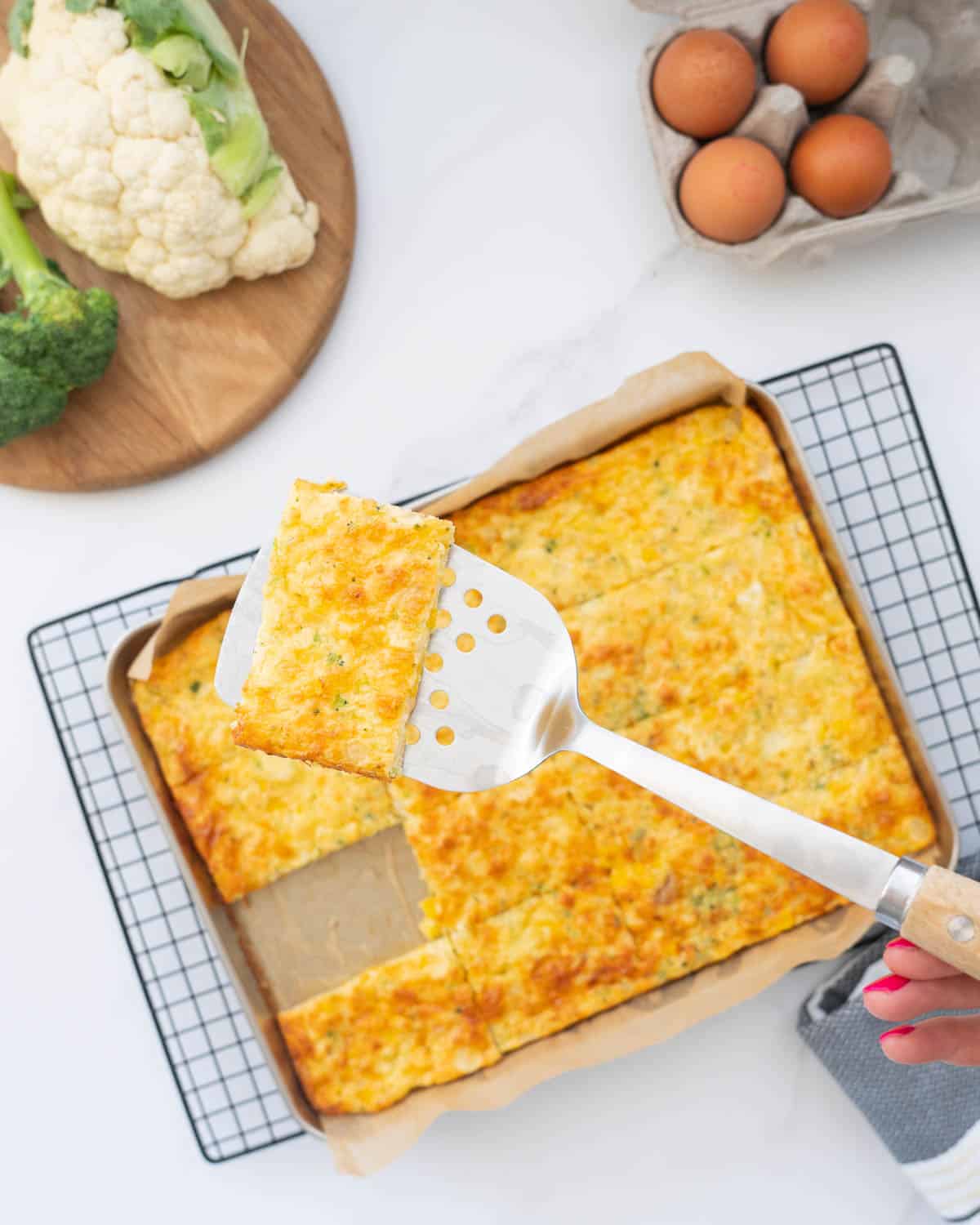 A slice of egg frittata on a stainless steel spatula.