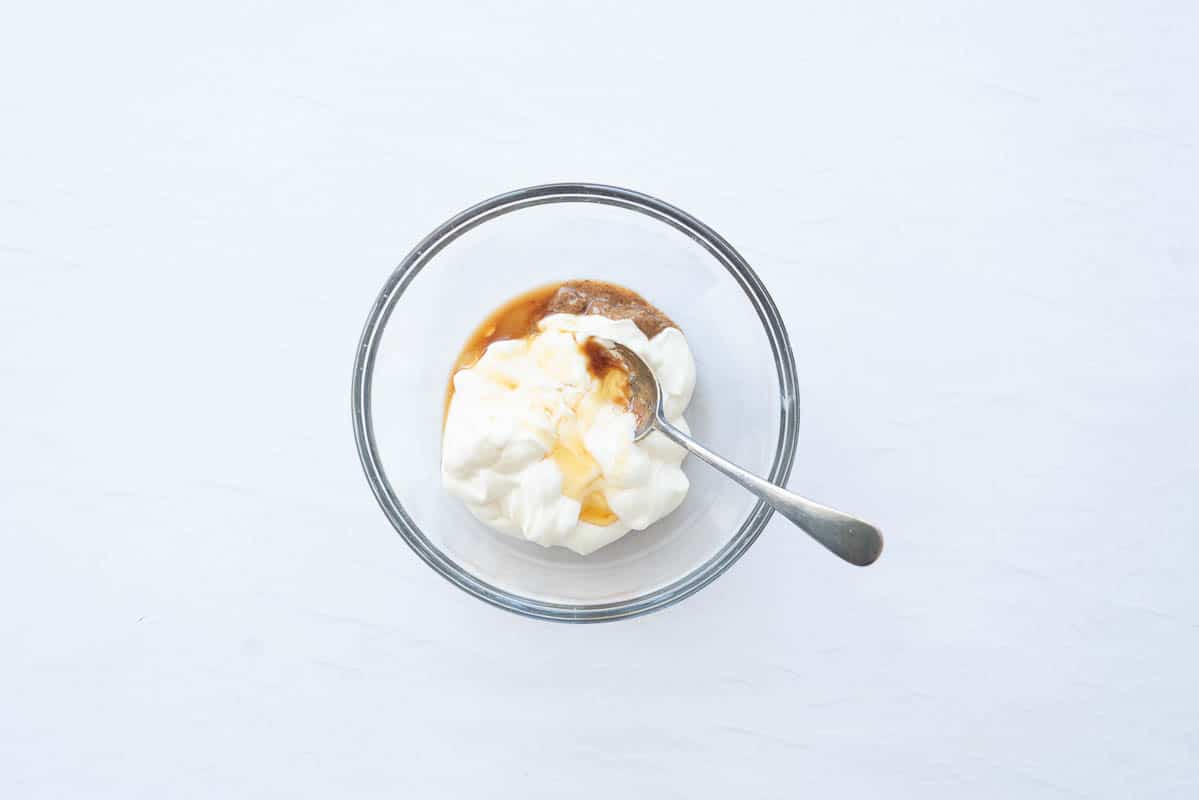 Yoghurt, almond butter, vanilla extract in a small glass mixing bowl.