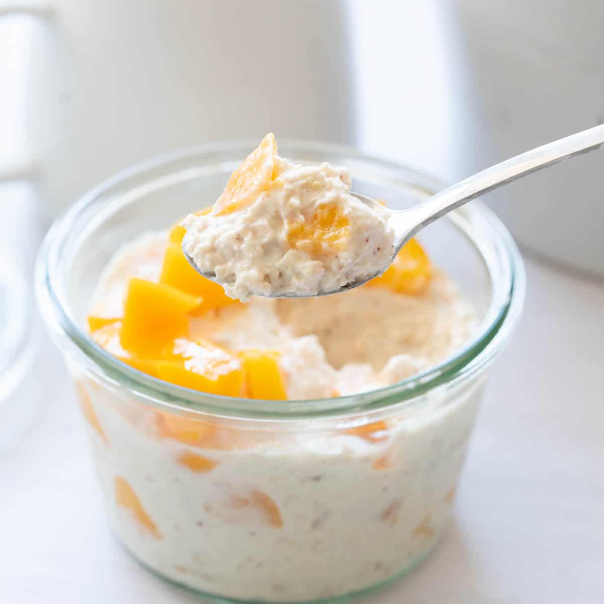 A spoonful of creamy white oats studded with small pieces of peach.