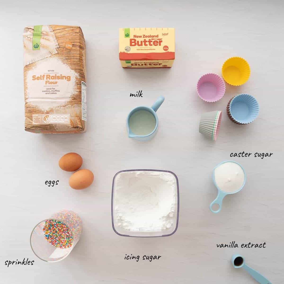 The ingredients to make vanilla cupcakes and vanilla glaze laid out on a bench top with text overlay.