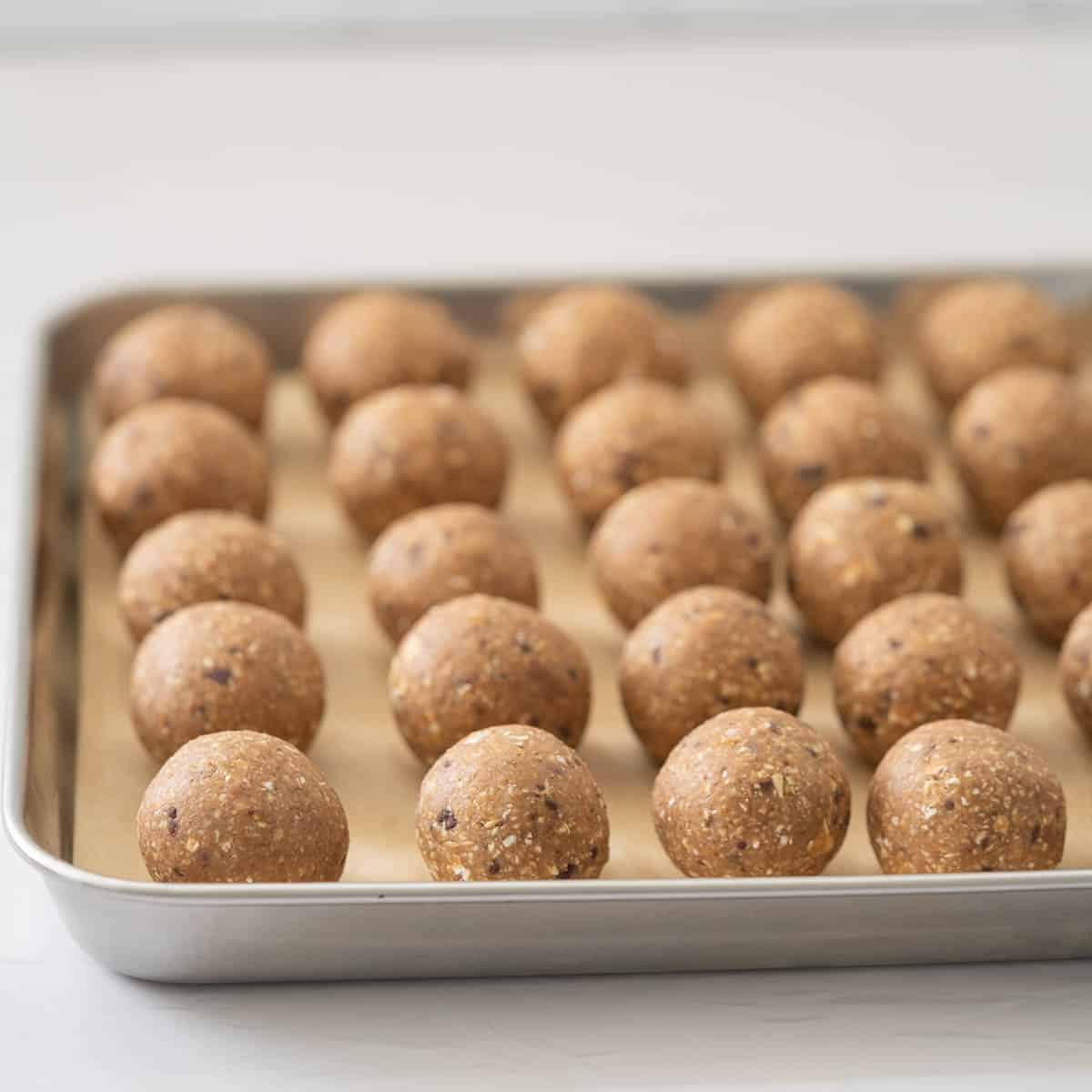 Vegan banana bread balls on a lined baking tray ready to go in the fridge.