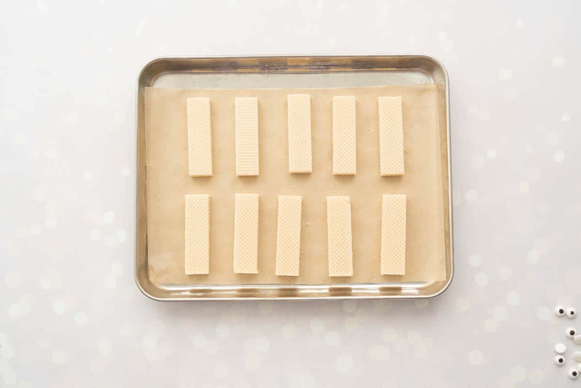 Ten vanilla wafer biscuits laid out on a parchment paper lined tray.