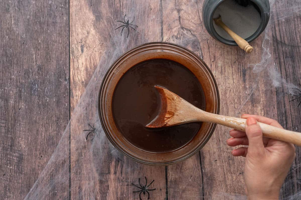 A glass mixing bowl full of smooth chocolate ganache.