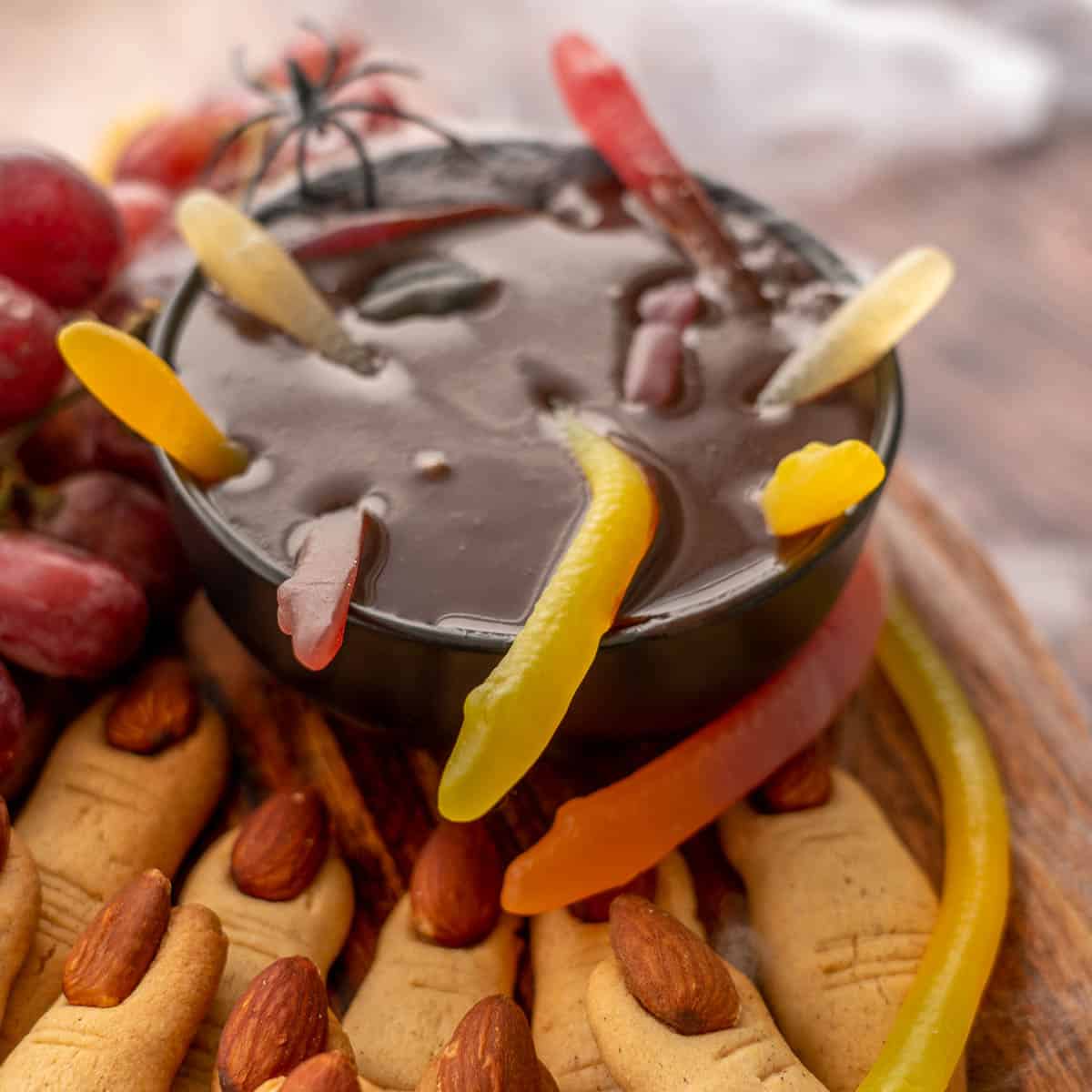 A bowl of chocolate ganache decorated with sweets including snackes to look like witches brew.