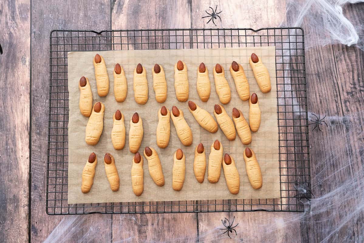 Witch finger cookies on a lined baking tray cooling on a rack. 