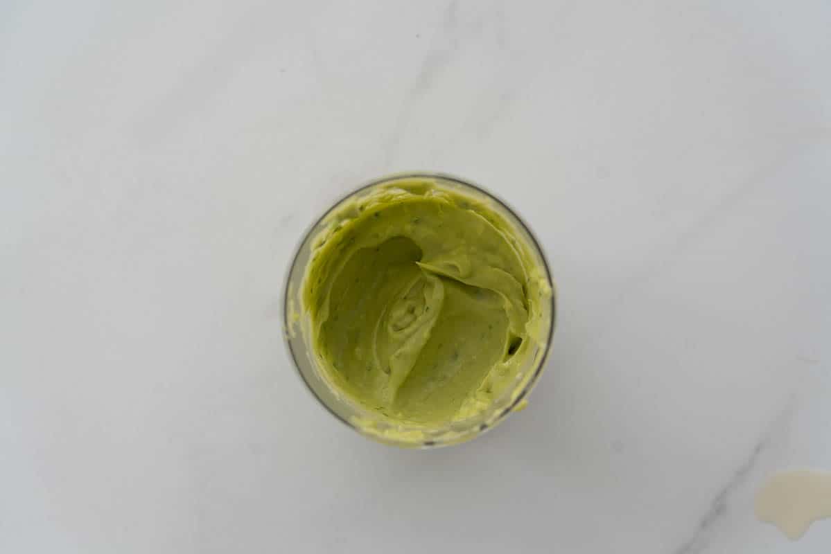 A blender cup full of smooth avocado purée.