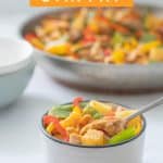 Pinepple chicken stir fry in a bowl on a white bench top with text over lay