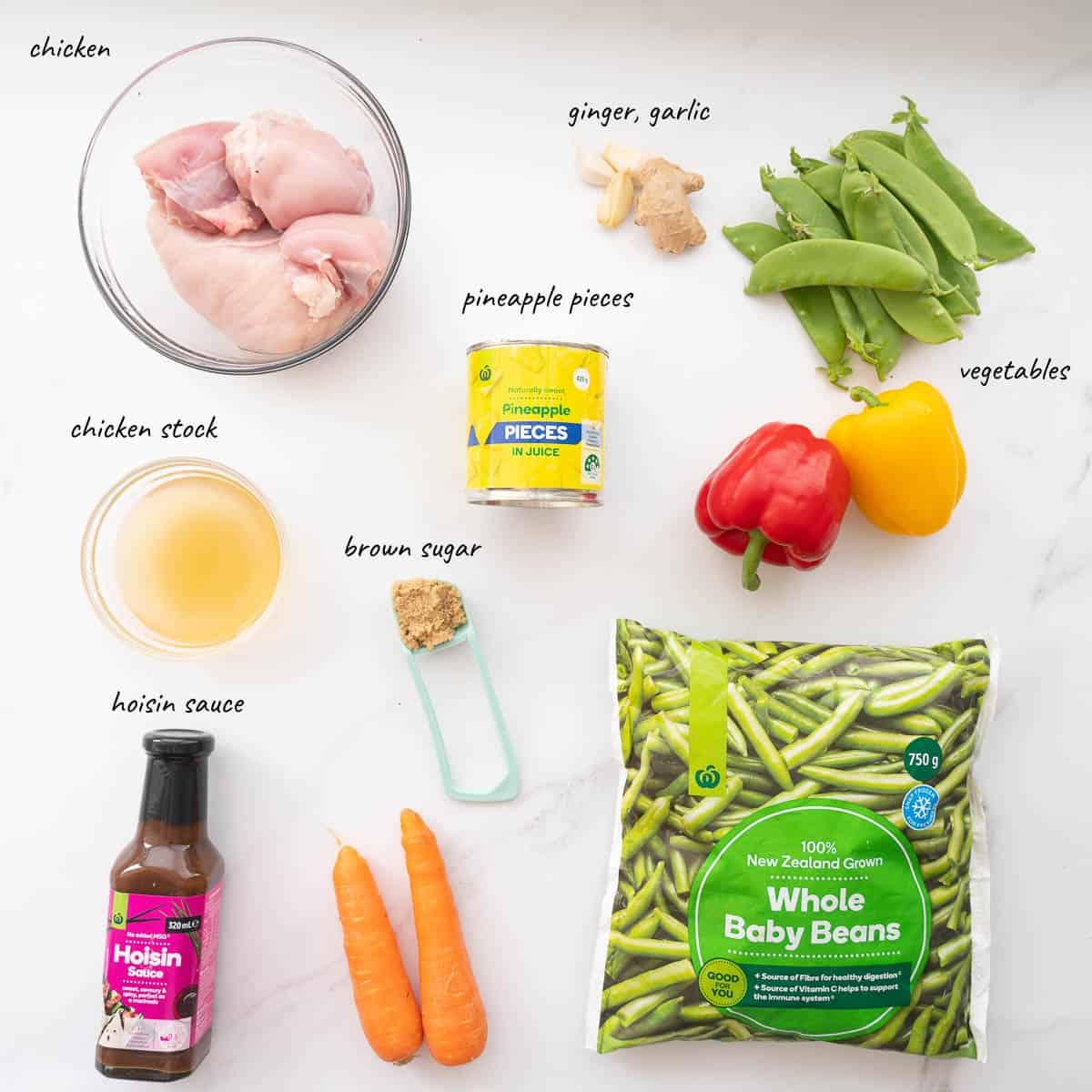 The ingredients to make pineapple chicken stir fry laid out on a bench top with text overlay.