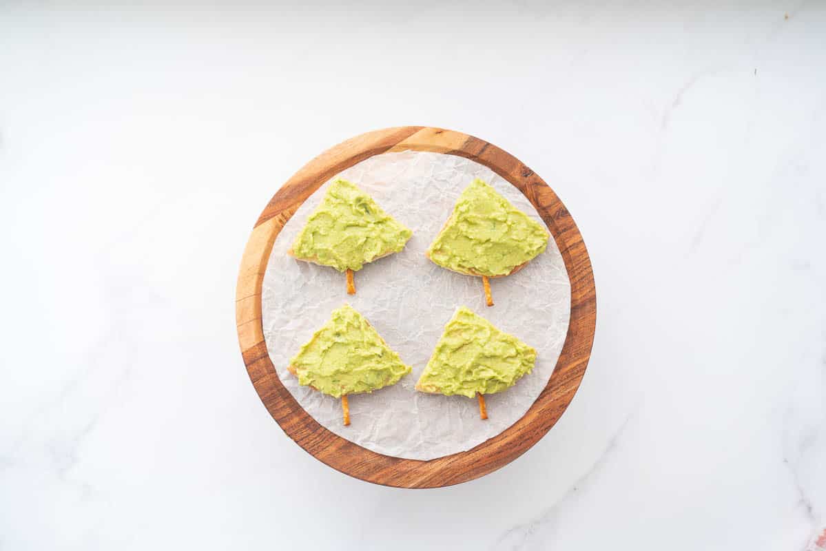 4 triangular pieces of pita bread spread with avocado to look like trees.