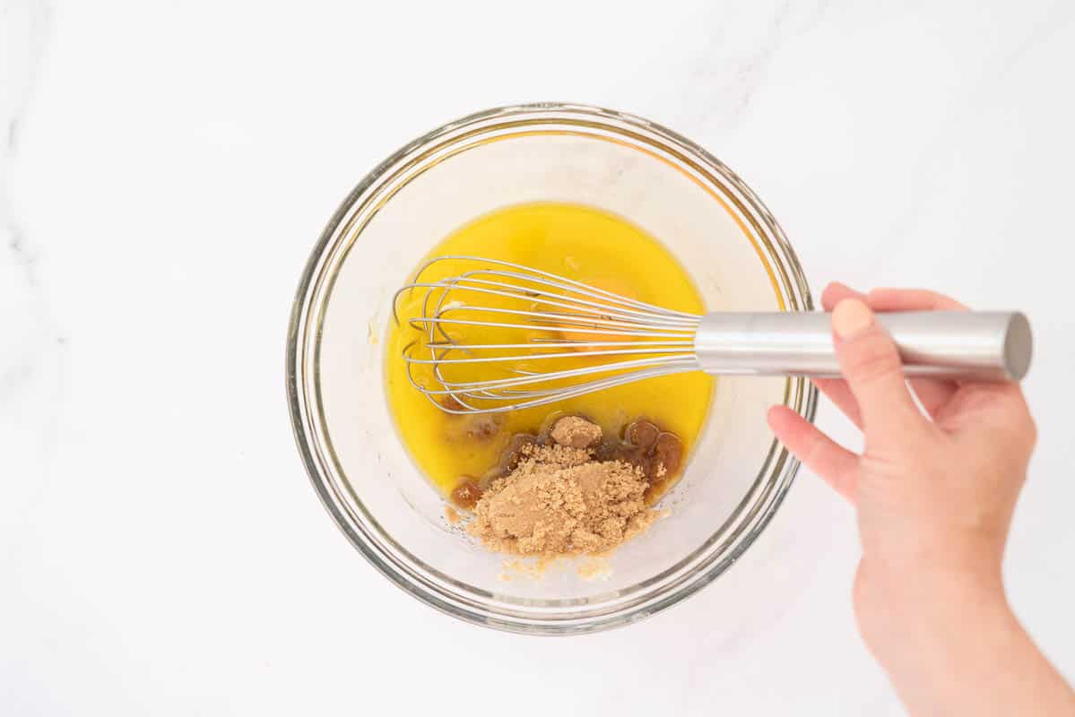 Melted butter, brown sugar and an egg in a large glass mixing bowl.