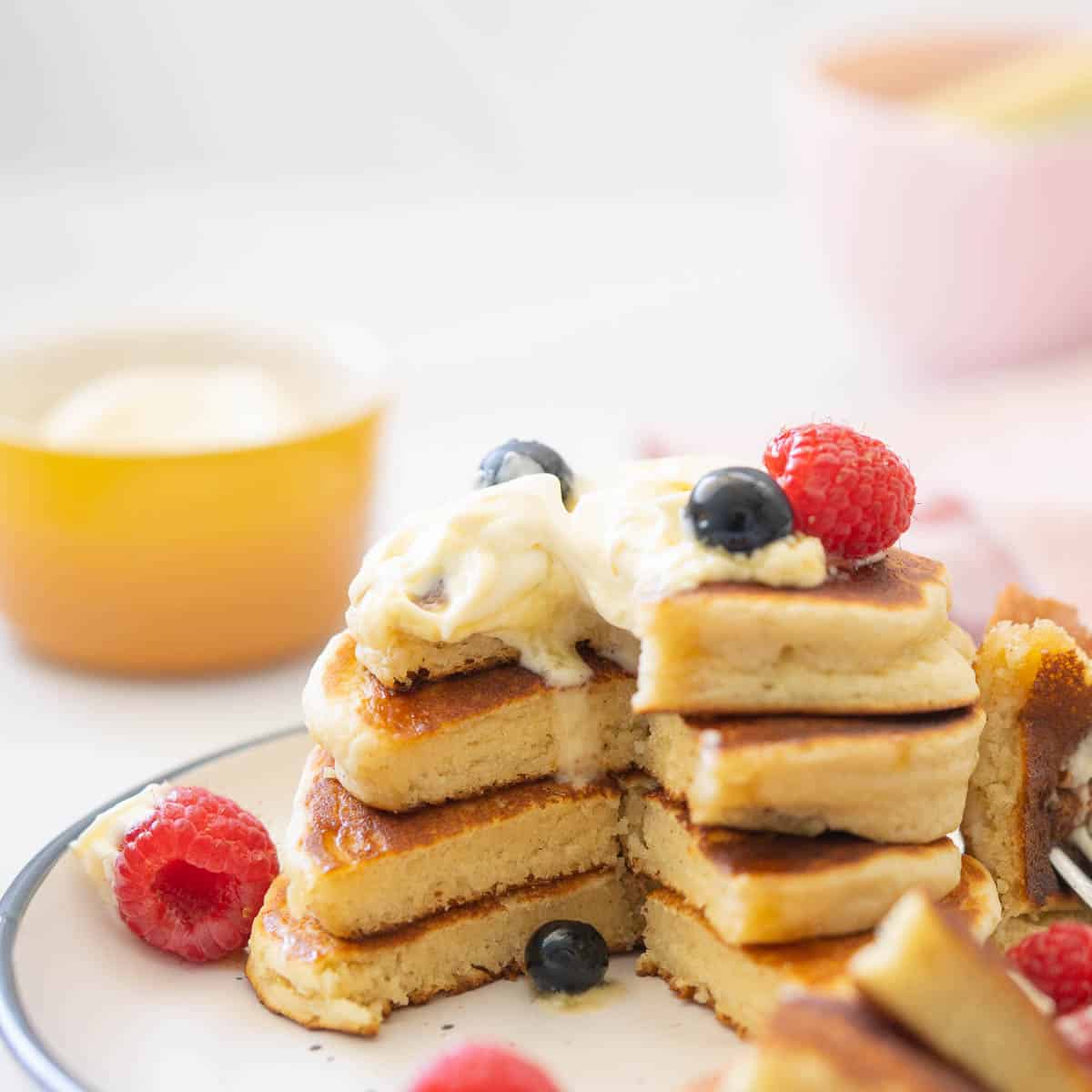 A stack of four pancakes with a wedge cut out from them so you can see the light fluffy texture. 